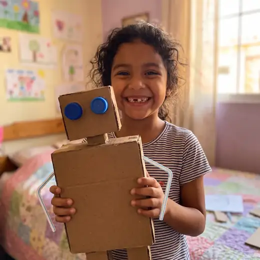 Una niña muestra orgullosa su robot de cartón